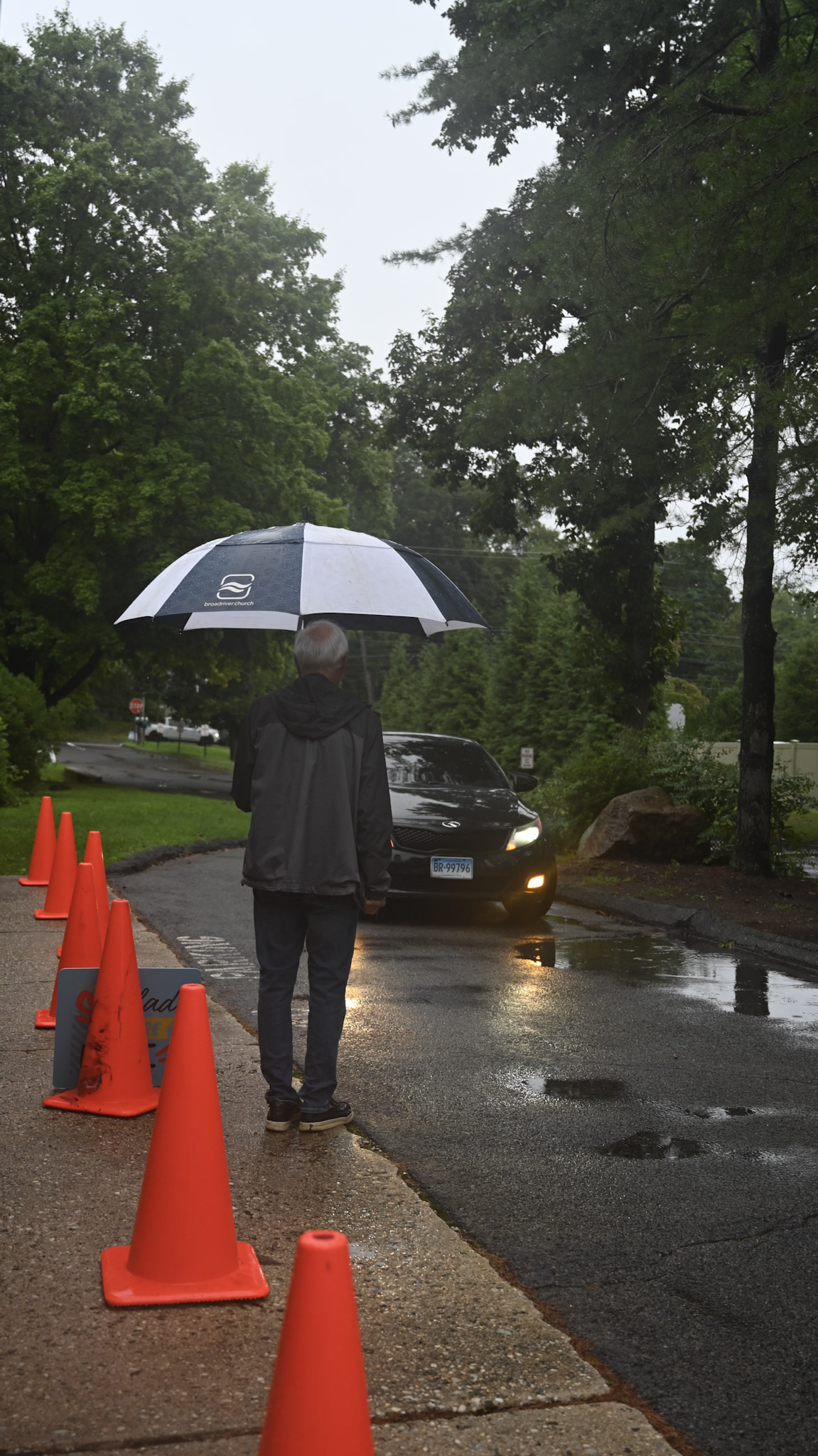 Un integrante del equipo de estacionamiento recibe a los visitantes bajo la lluvia