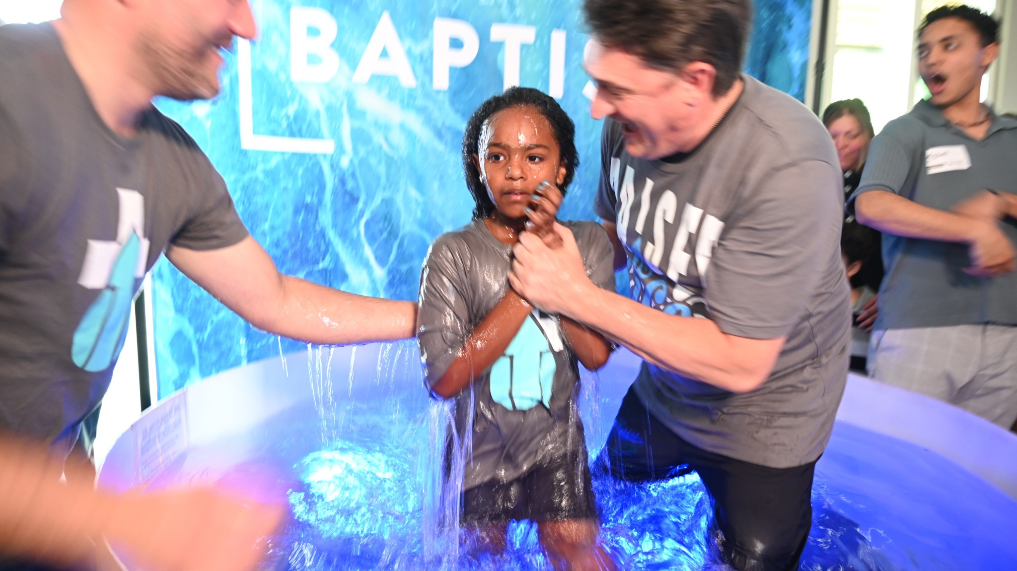 A child comes up from the water with the baptism team at Broad River Church.