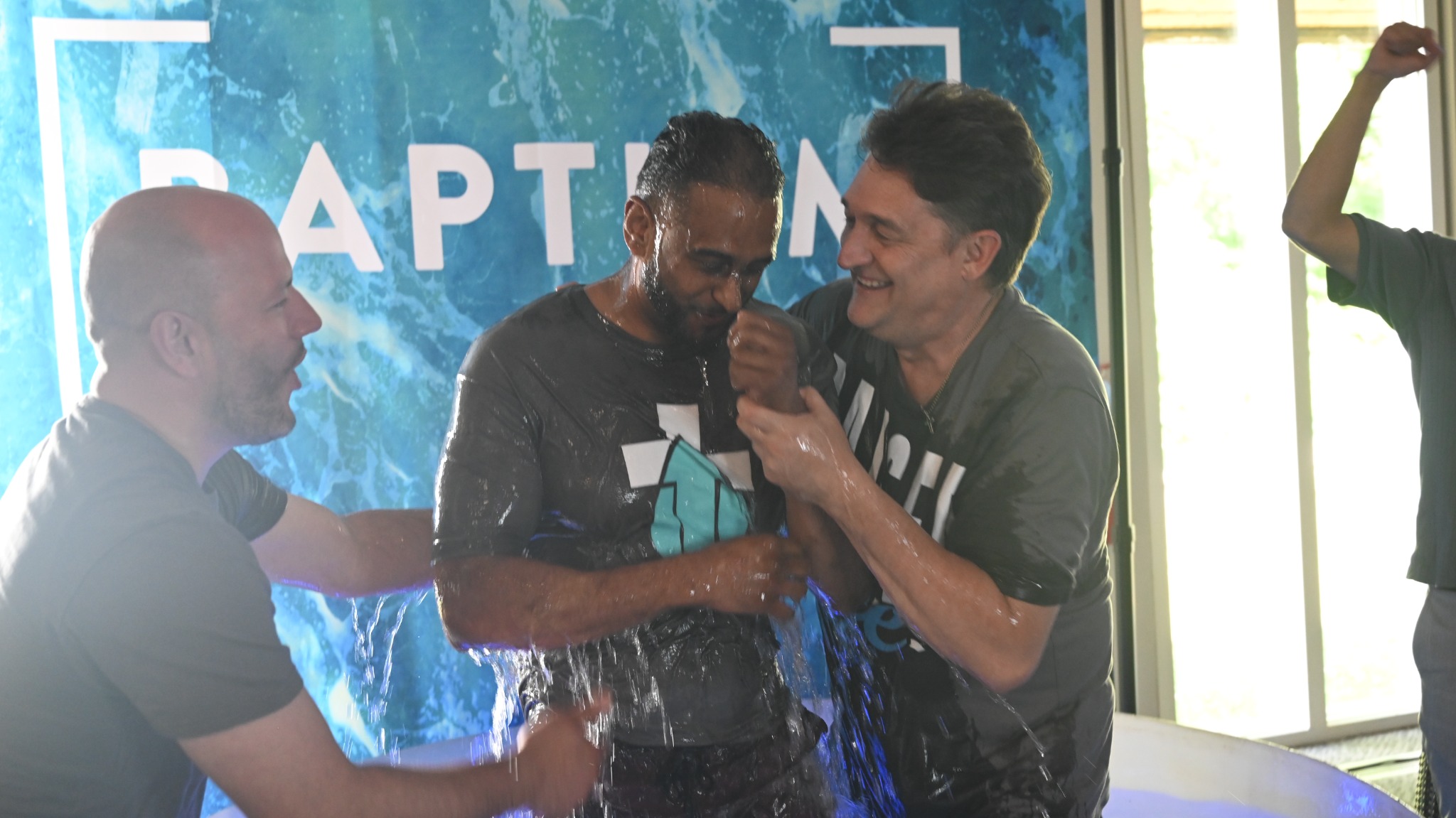 A man comes up from the water as the baptism team celebrates at Broad River Church.