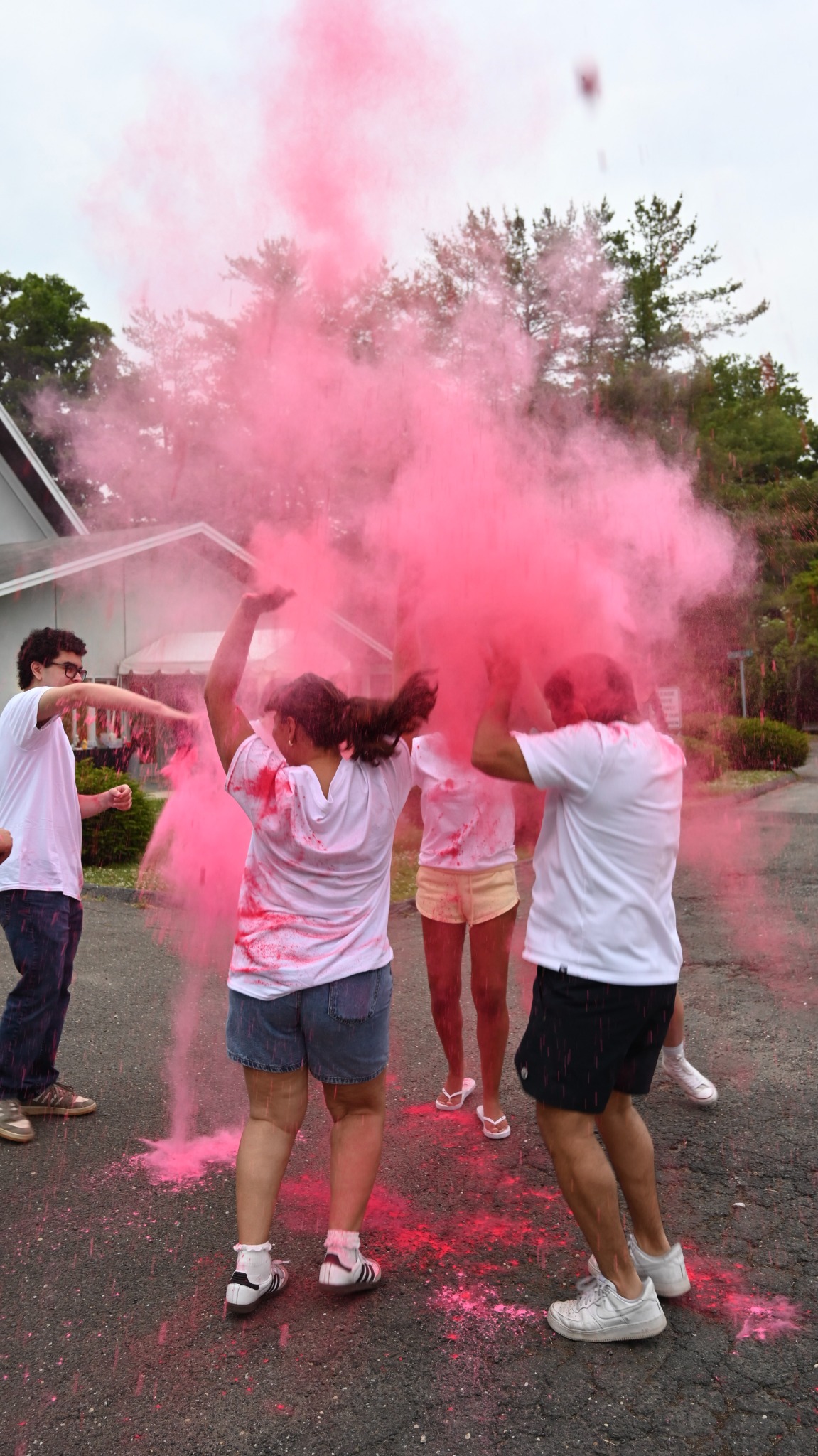 Students tossing pink color powder during an outdoor activity