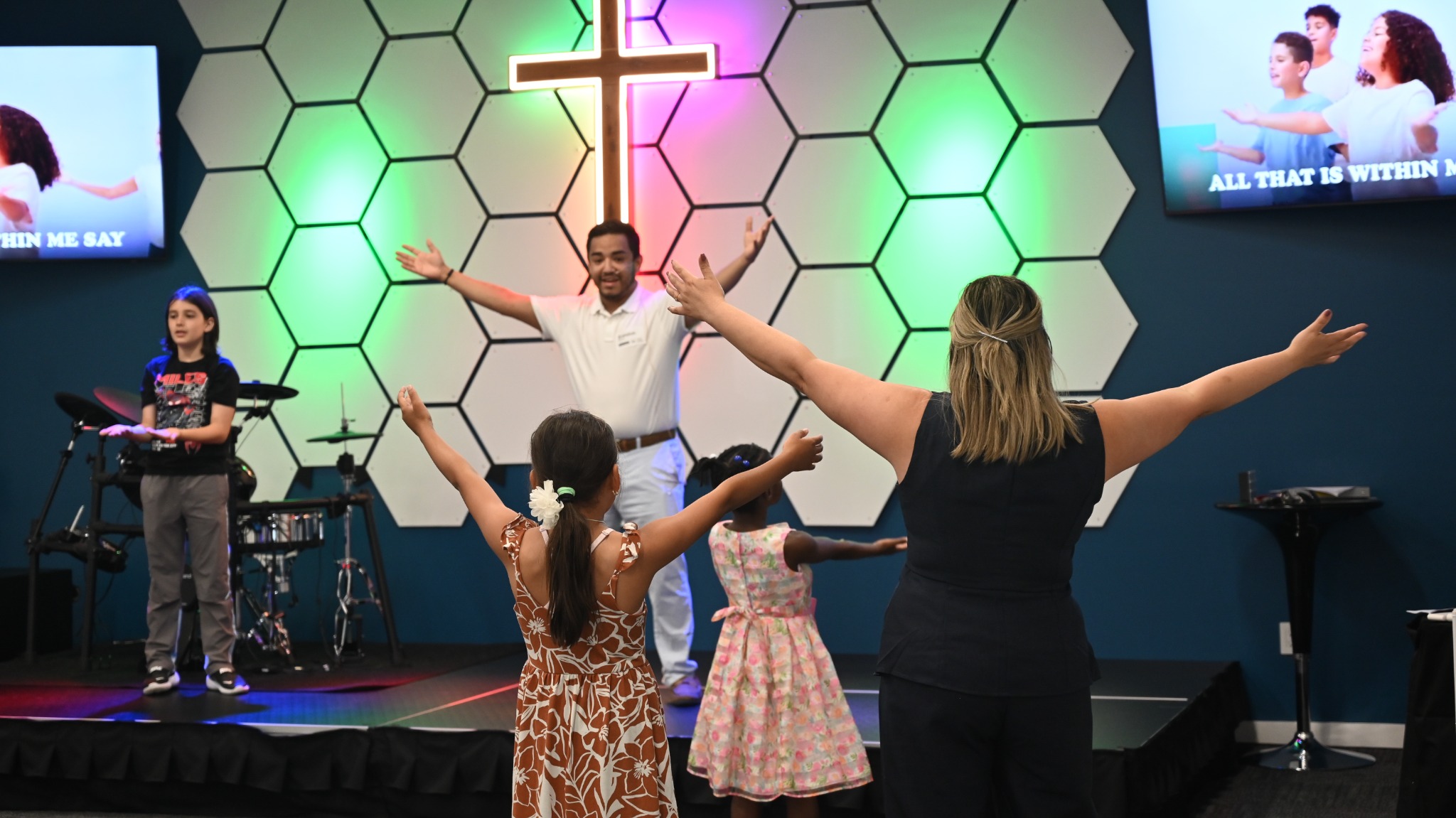 Children and leaders raising their hands during Kids worship