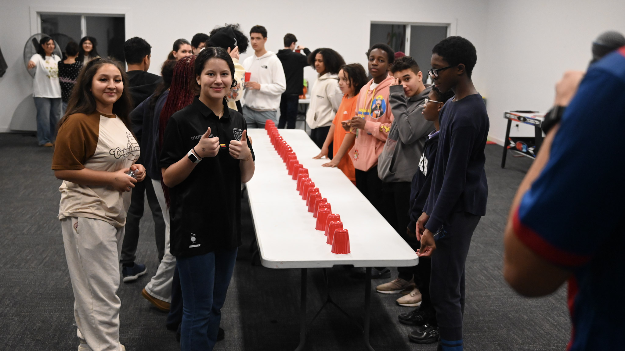 Students smiling and gathering around a table for a group game