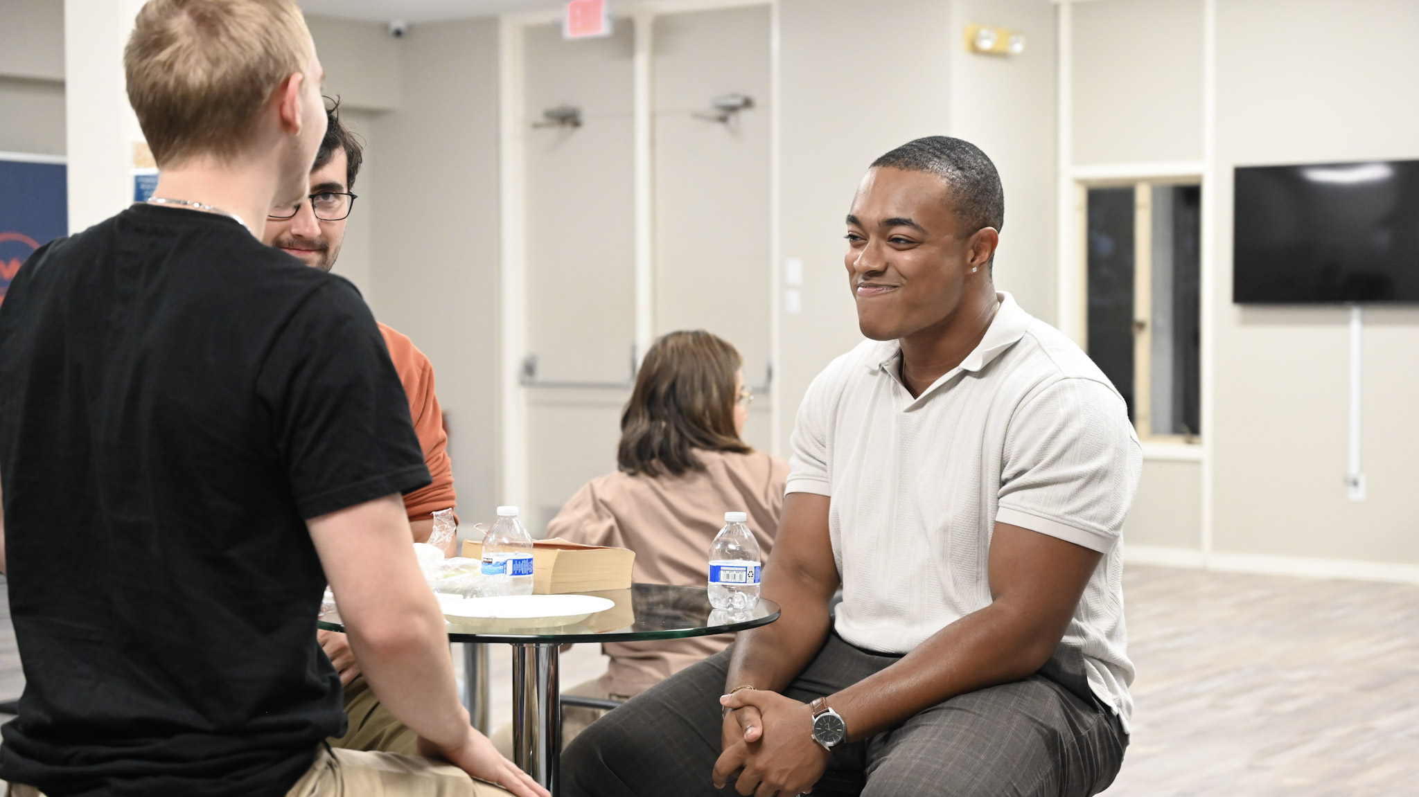 Young adults sharing conversation around a table at Broad River