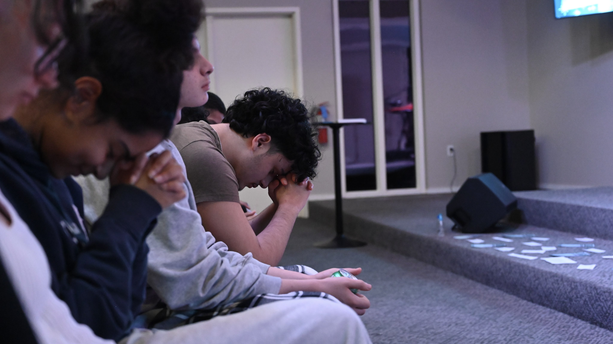 Students seated together with heads bowed in prayer