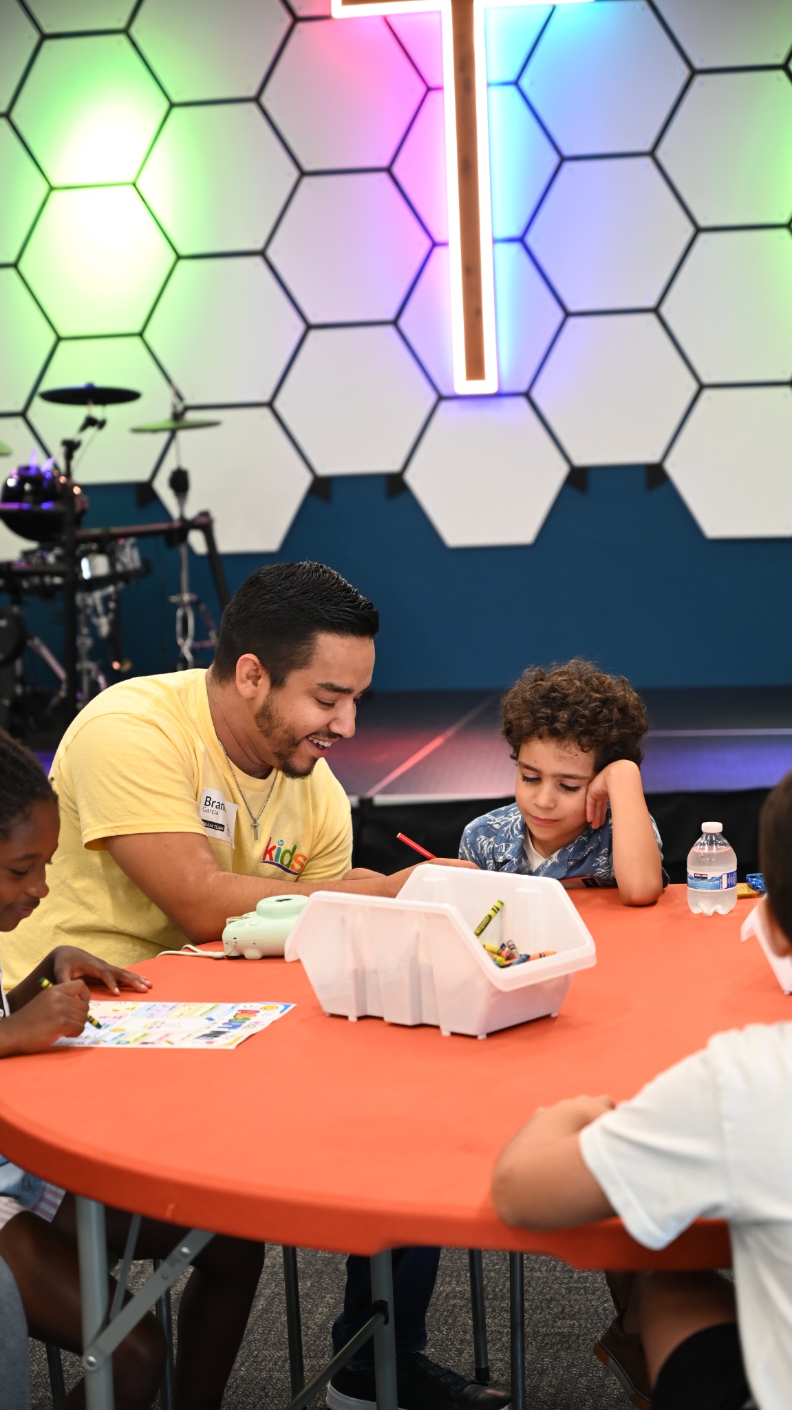 A leader helping children with an activity at a table