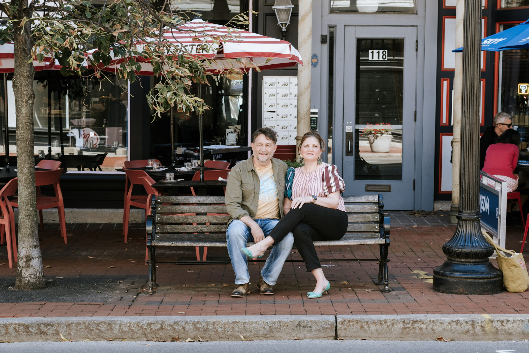 Kevin and Jacinta Mullins seated together on a bench outside a café.