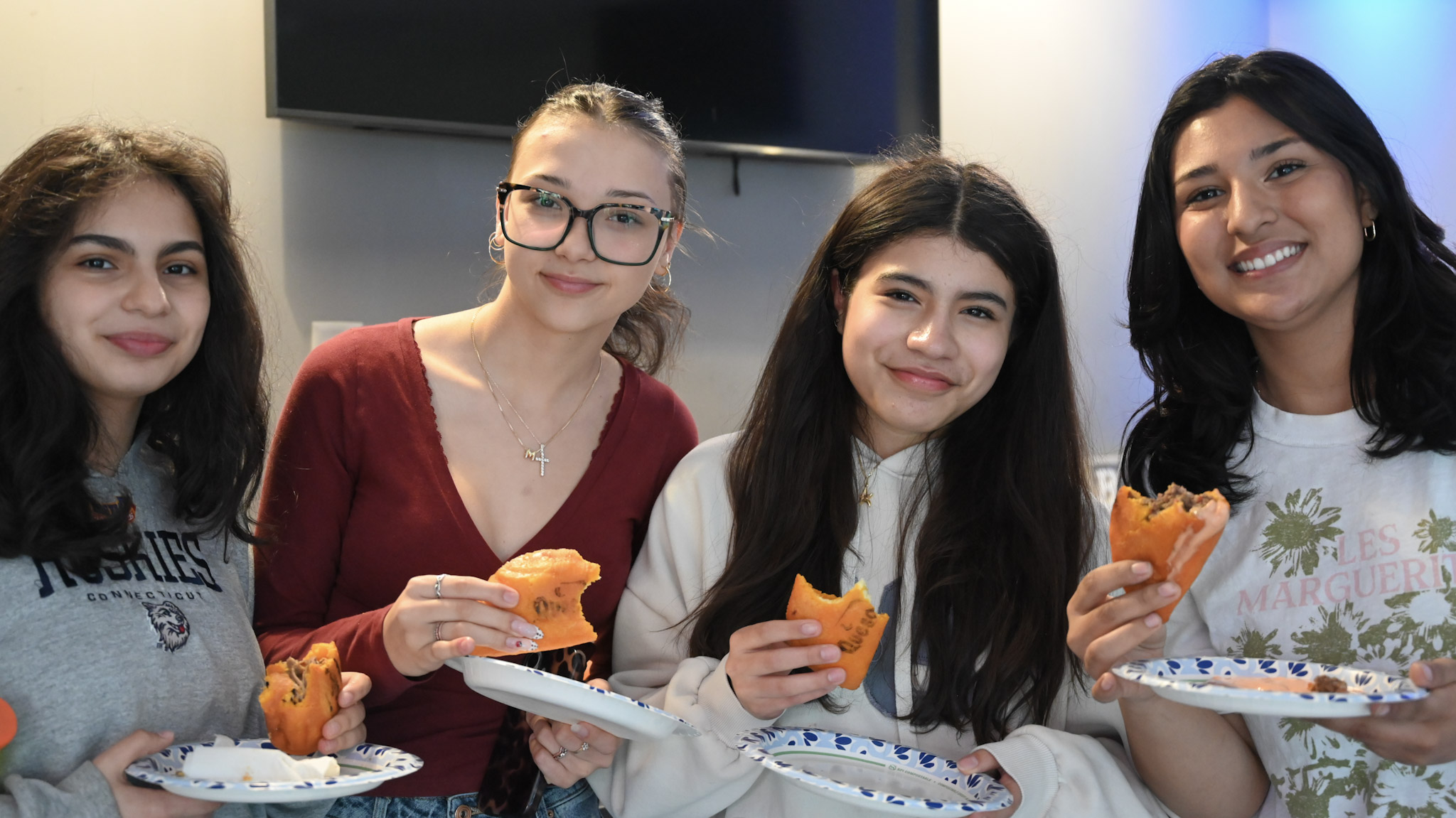 Four students smiling together while sharing food