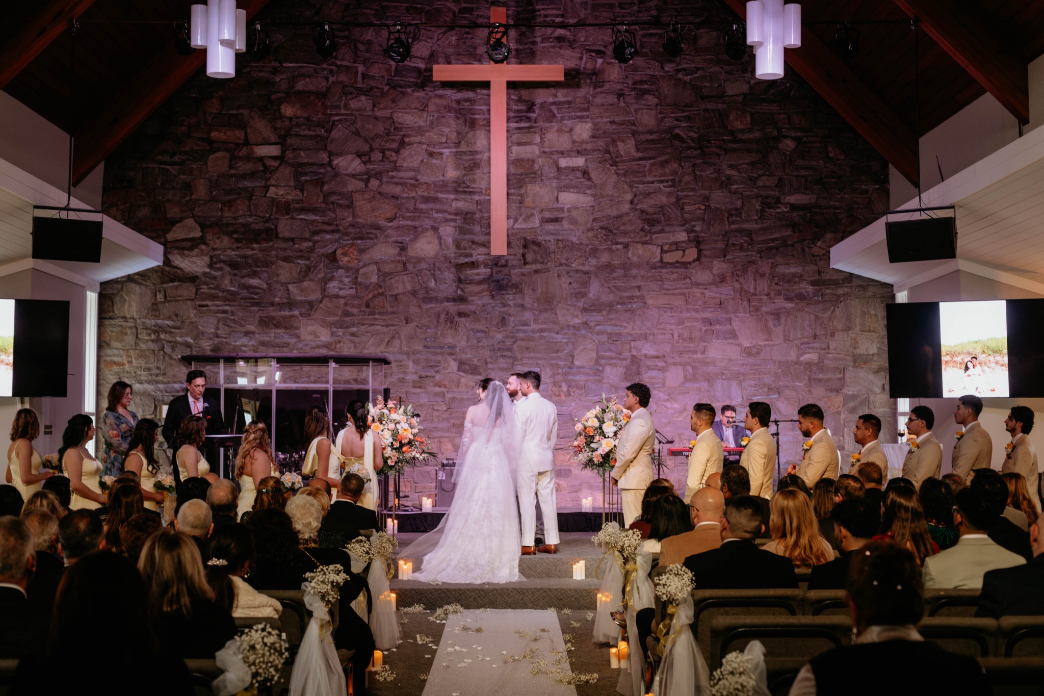 Wide view of a wedding ceremony and guests beneath the cross at Broad River Church