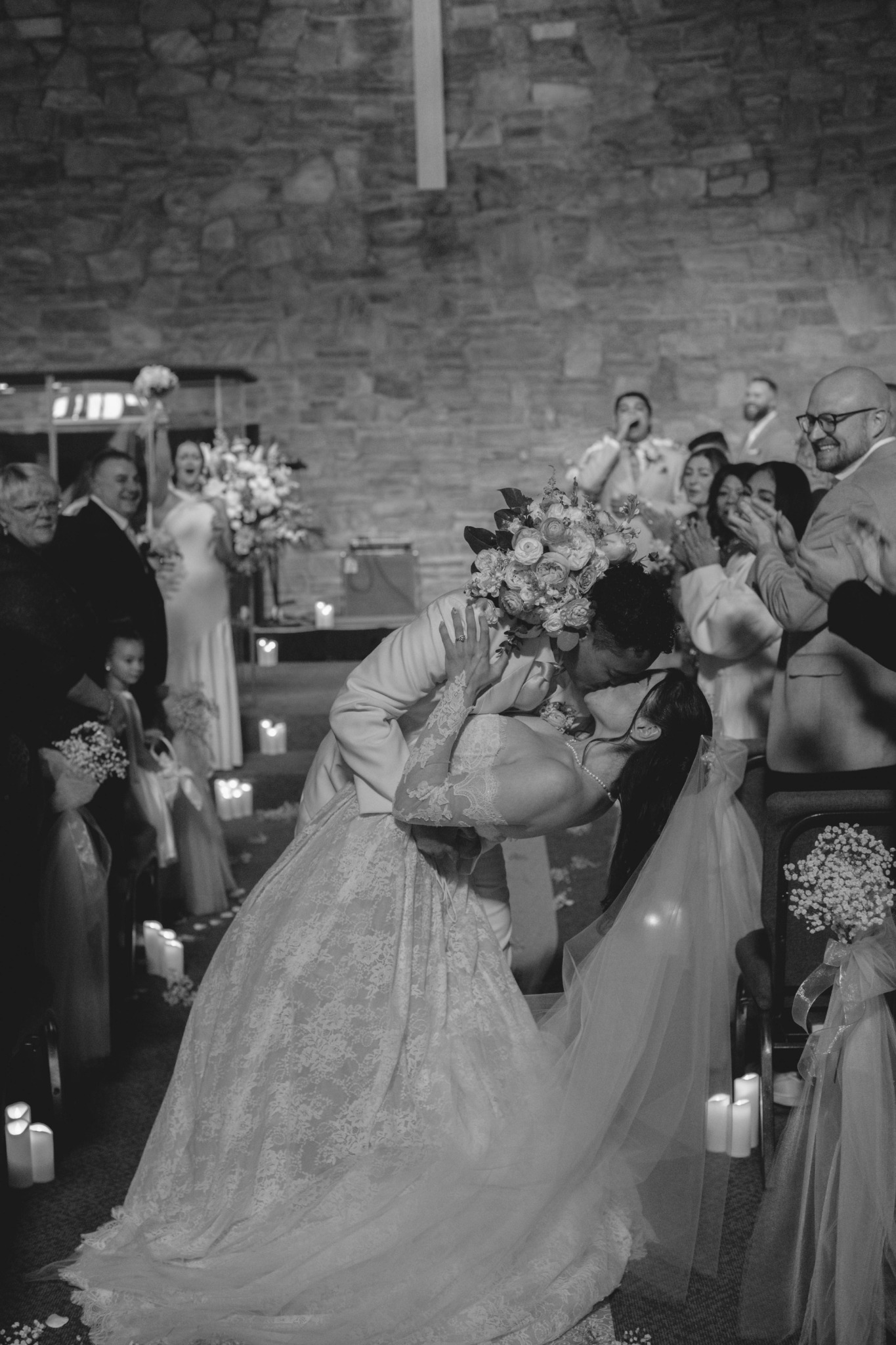 Newlyweds kissing in the decorated aisle as guests celebrate