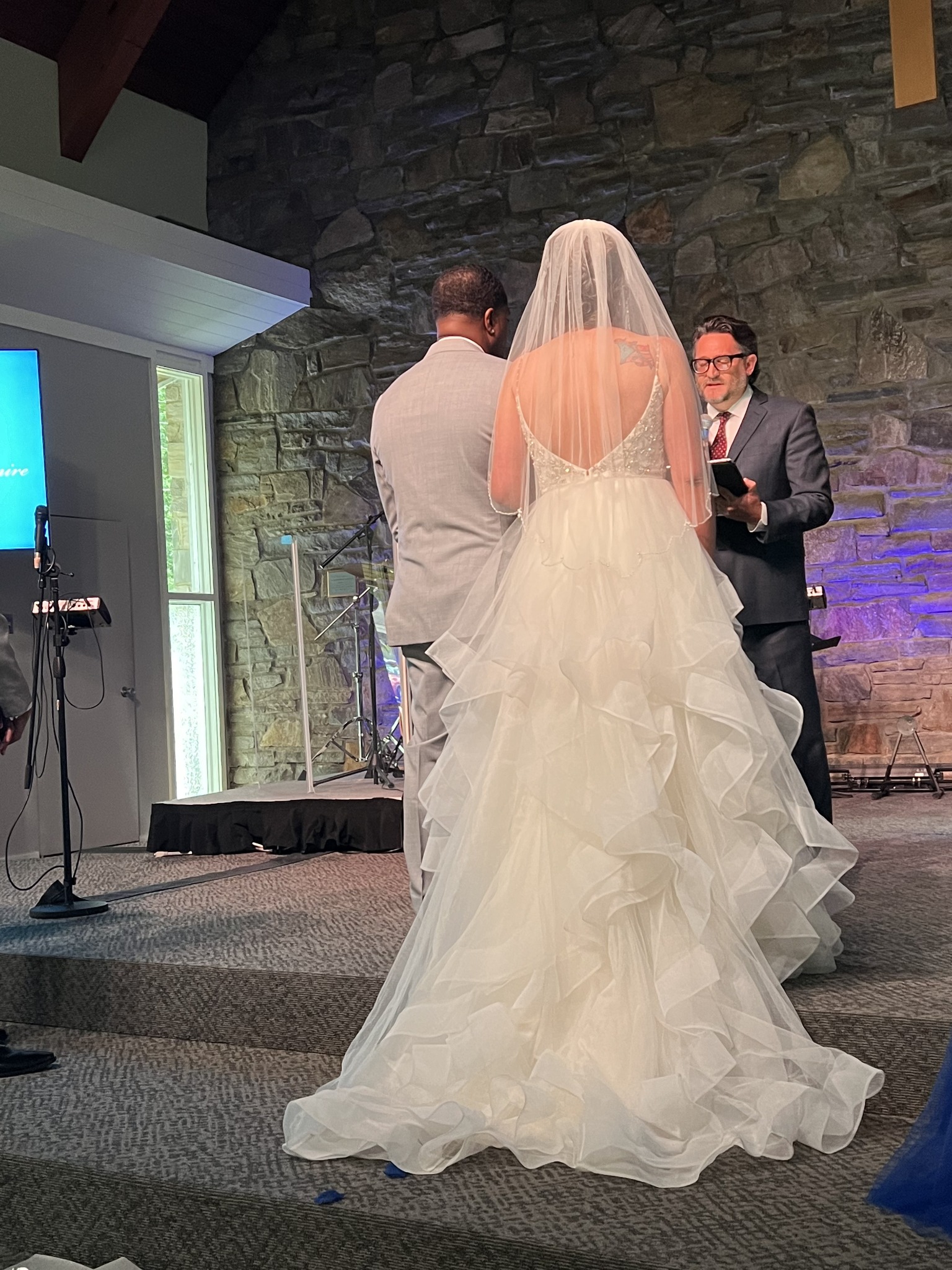 A bride and groom facing Kevin during their wedding ceremony at Broad River Church