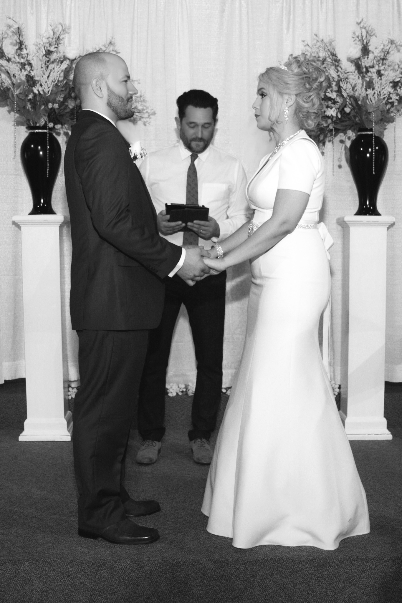 Black-and-white photograph of a couple holding hands during their ceremony