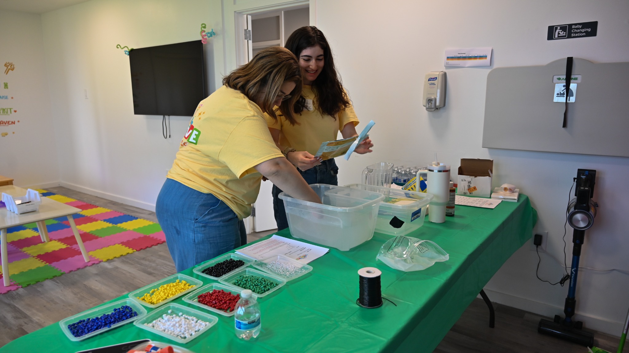 Two Kids volunteers preparing craft supplies at a table.