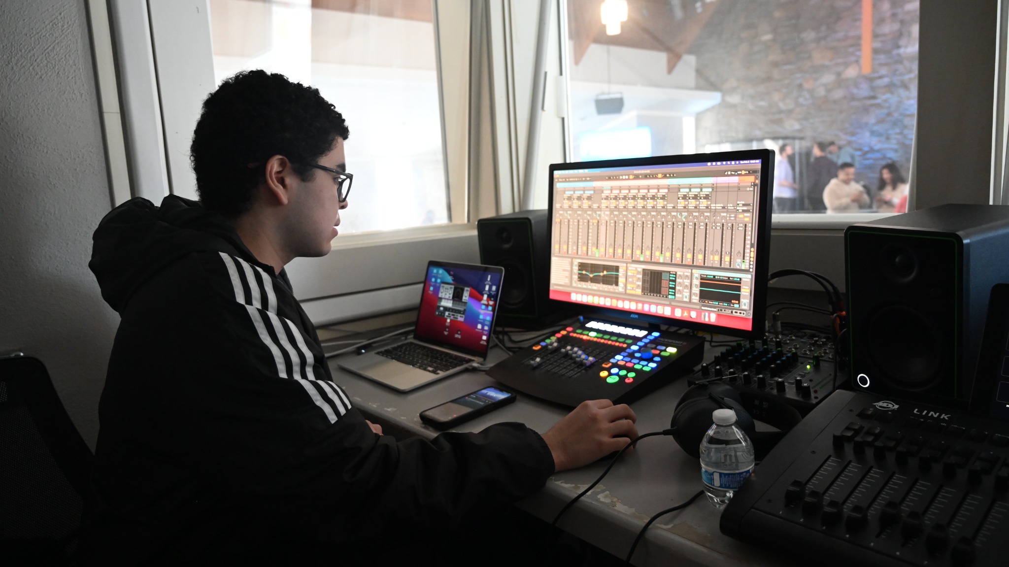 A production volunteer operating audio equipment and a computer.