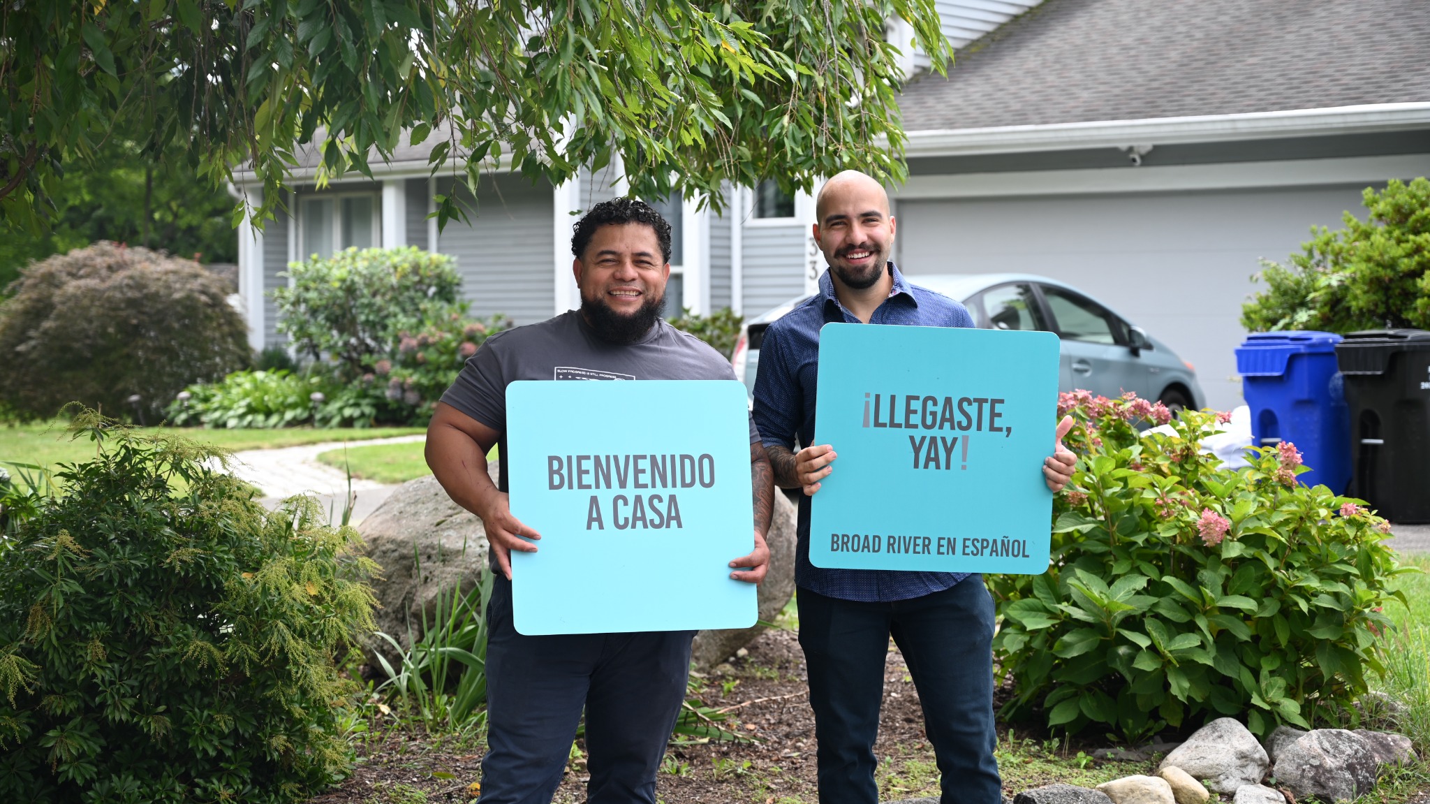 Two volunteers holding Spanish-language welcome signs outside the church.